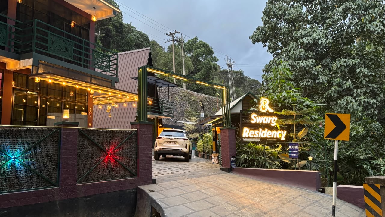 The warmly lit entrance to Swarg Residency nestled in greenery